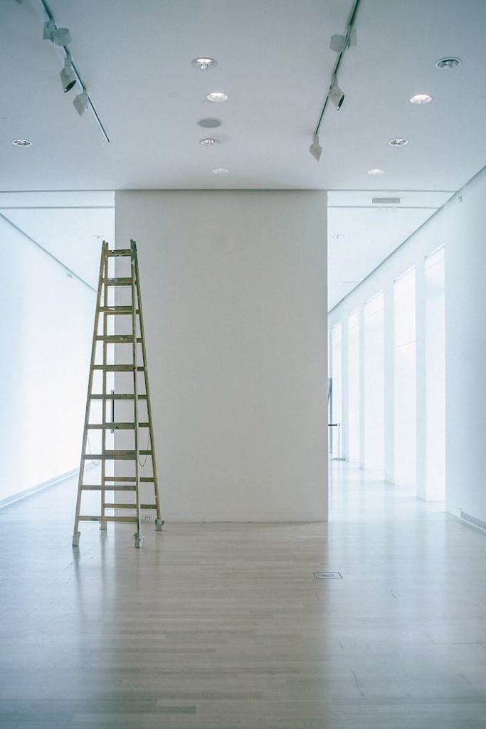 Wide indoor space with a ladder, showcasing LED lighting and modern minimalism.