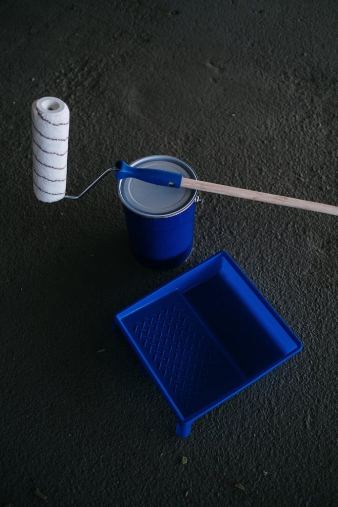 Paint roller, tray, and can on dark surface, ready for a DIY project.